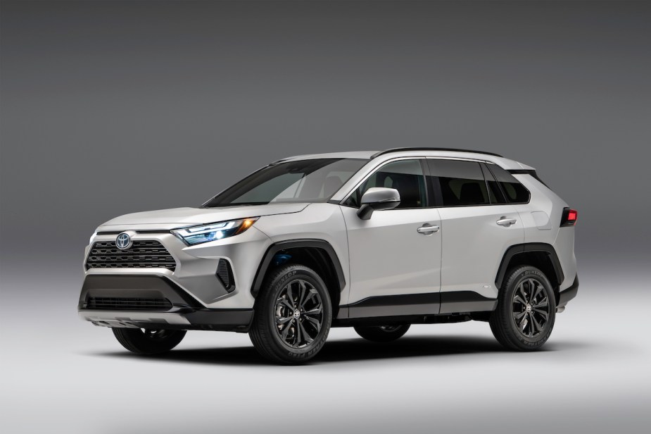 A silver 2023 Toyota RAV4 Hybrid parked in a black and white room. 