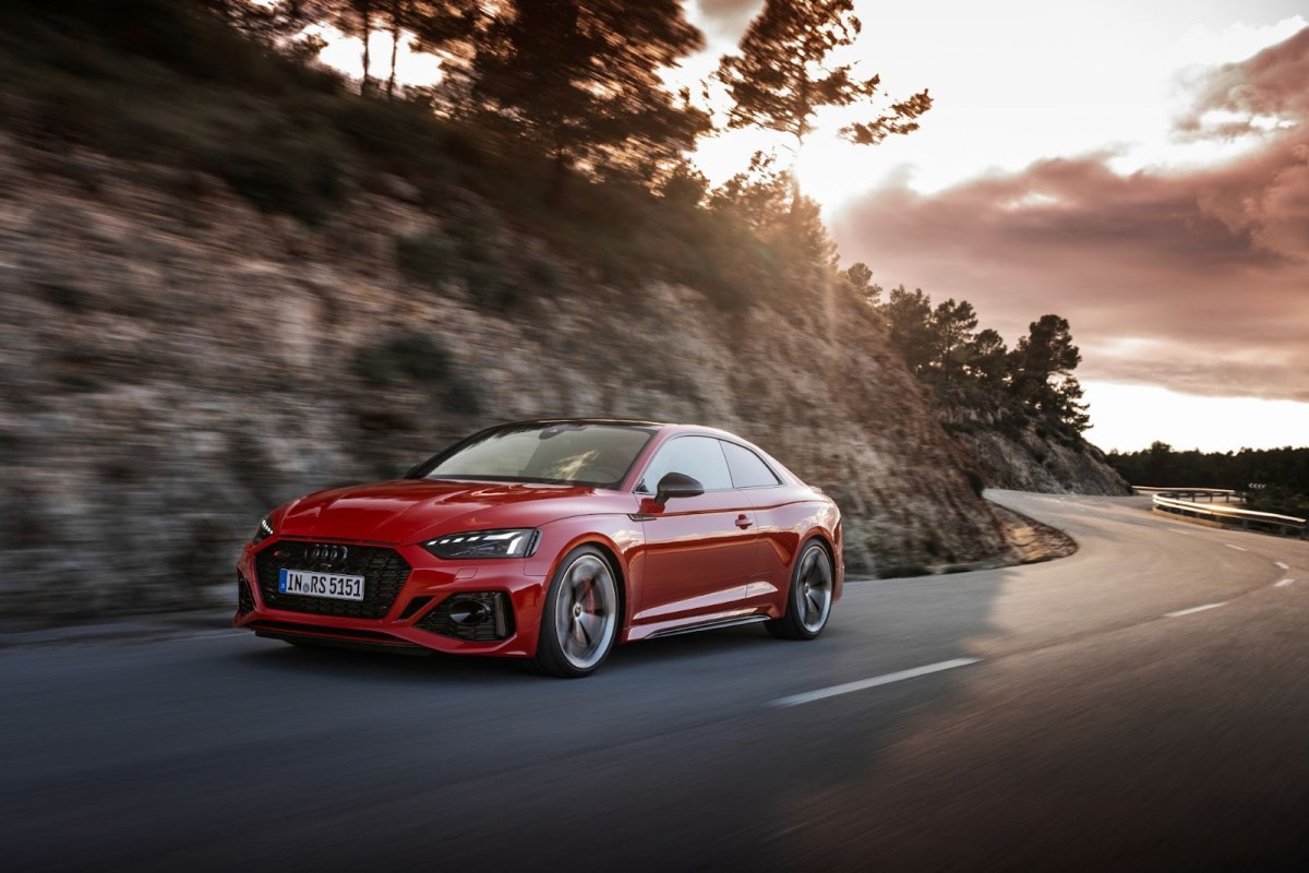 A red Audi RS 5 Competition on a windy mountain road.