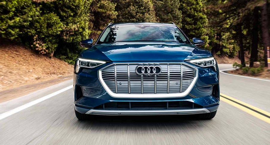 A blue 2023 Audi E Tron is driving on the road.