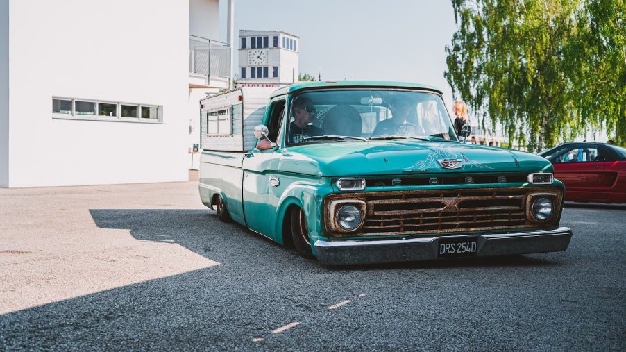 A turqoise pickup truck lowered to the ground.