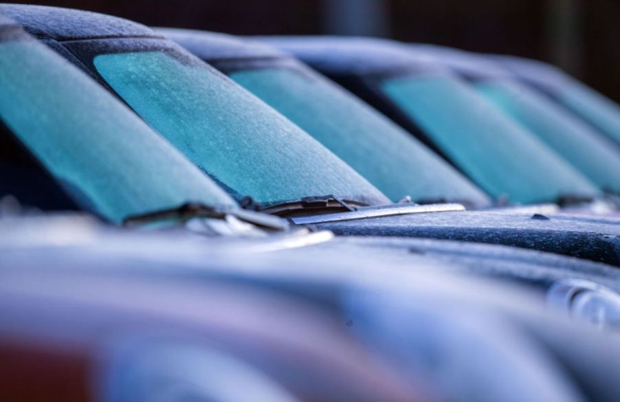 Cars in a parking lot with icy windshields.