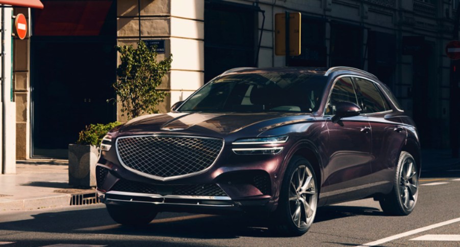 A black Genesis GV70 small luxury SUV is parked on the road.