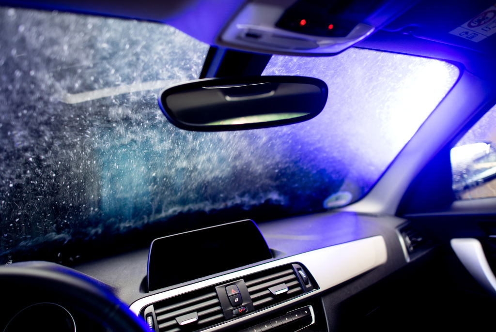 Interior shot of a car being washed with water running down the windshield.