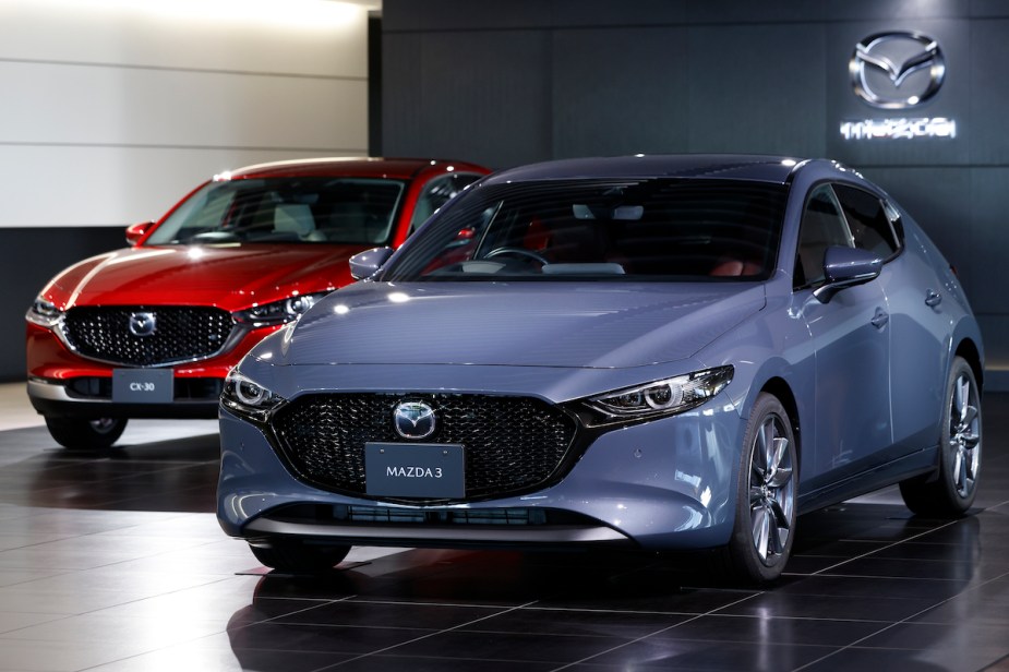 A light blue and red Mazda 3 parked indoors, which is one of the least expensive Mazdas to maintain. 