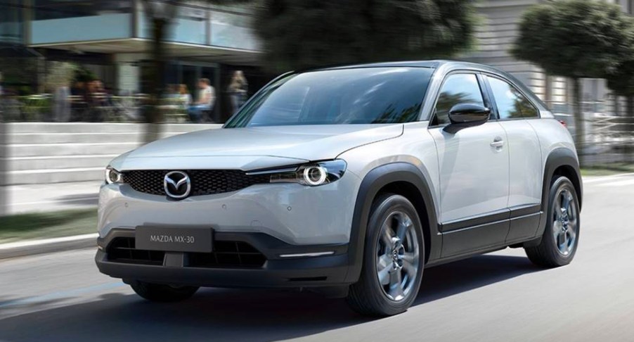 A gray 2023 Mazda MX-30 subcompact SUV is driving on the road.