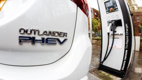 A Mitsubishi Outlander PHEV plugged into a charging station on a London street