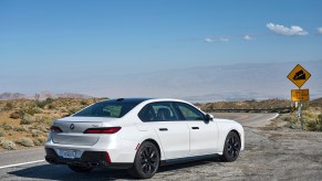 White BMW 7 Series from the rear-quarter position, on a desert backdrop