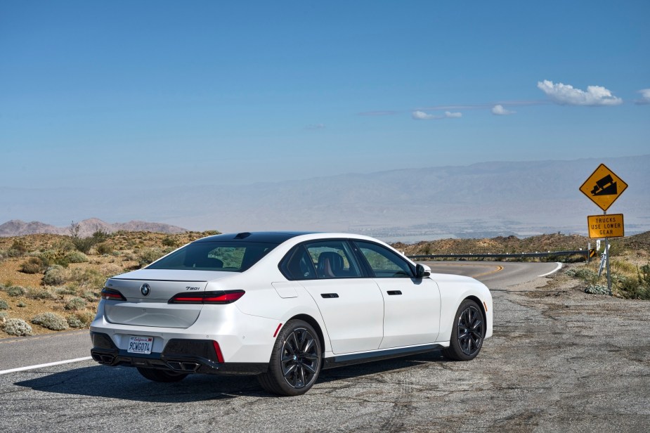 White BMW 7 Series from the rear-quarter position, on a desert backdrop