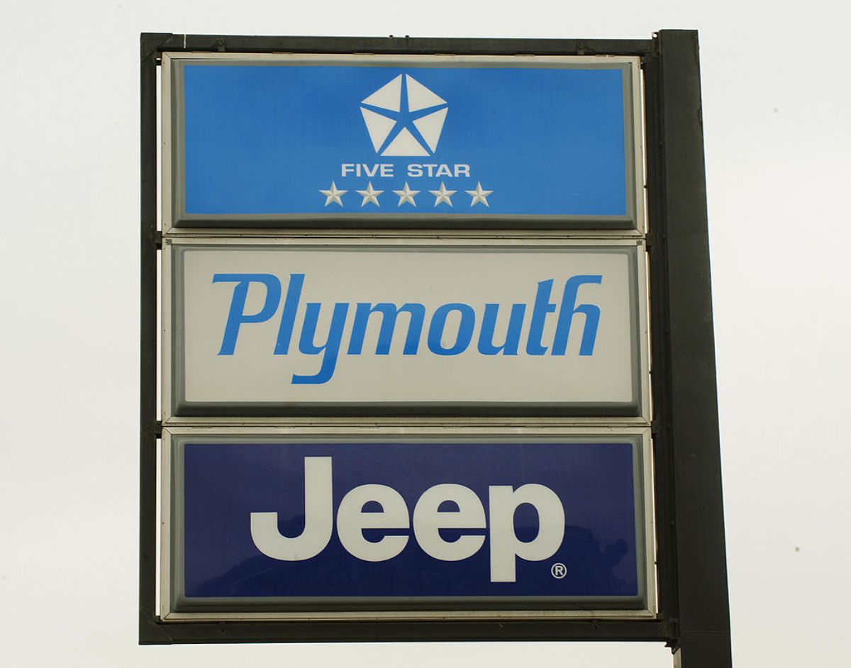 A Chrysler, Plymouth and Jeep sign outside a car dealership.