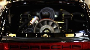 Closeup of the engine bay of a black Porsche 911 with its air cooled flat-six engine.