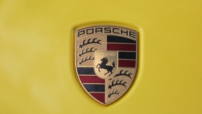 Porsche crest logo set against a yellow background.