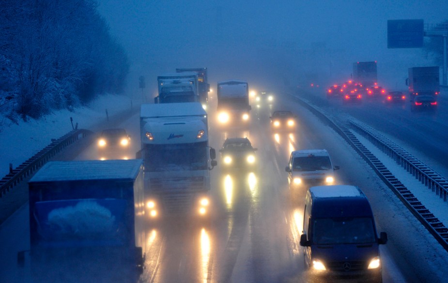 Semi truck drivers navigating a snow-covered interstate highway.