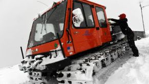 A woman unloads a snow-covered snowcat