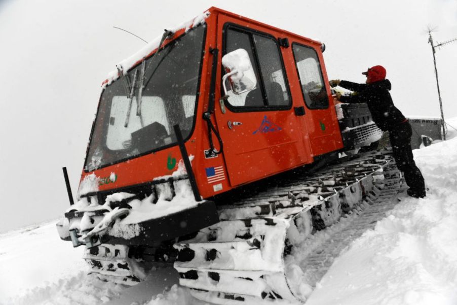 A woman unloads a snow-covered snowcat