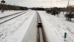 A lone car driving in a winter storm.