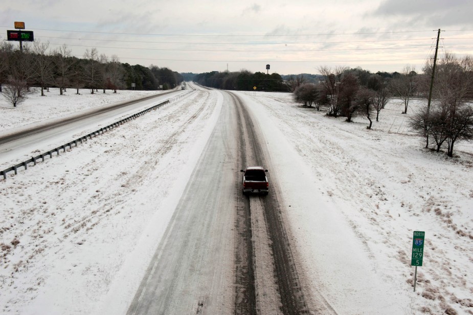 A lone car driving in a winter storm.