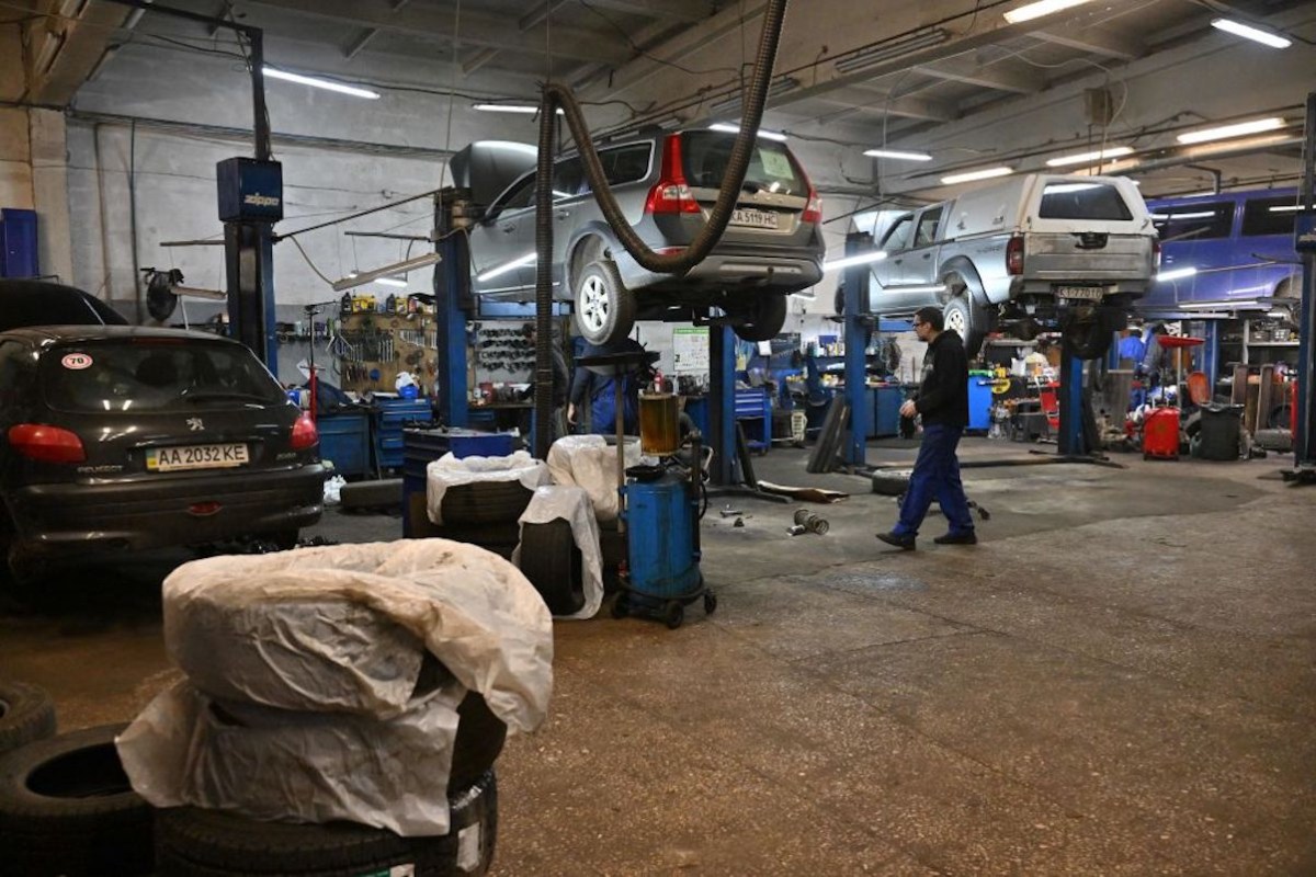 A mechanic working on cars in his auto shop.