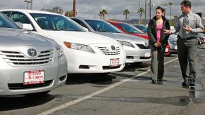 A car dealer showing used Toyota cars to a customer.