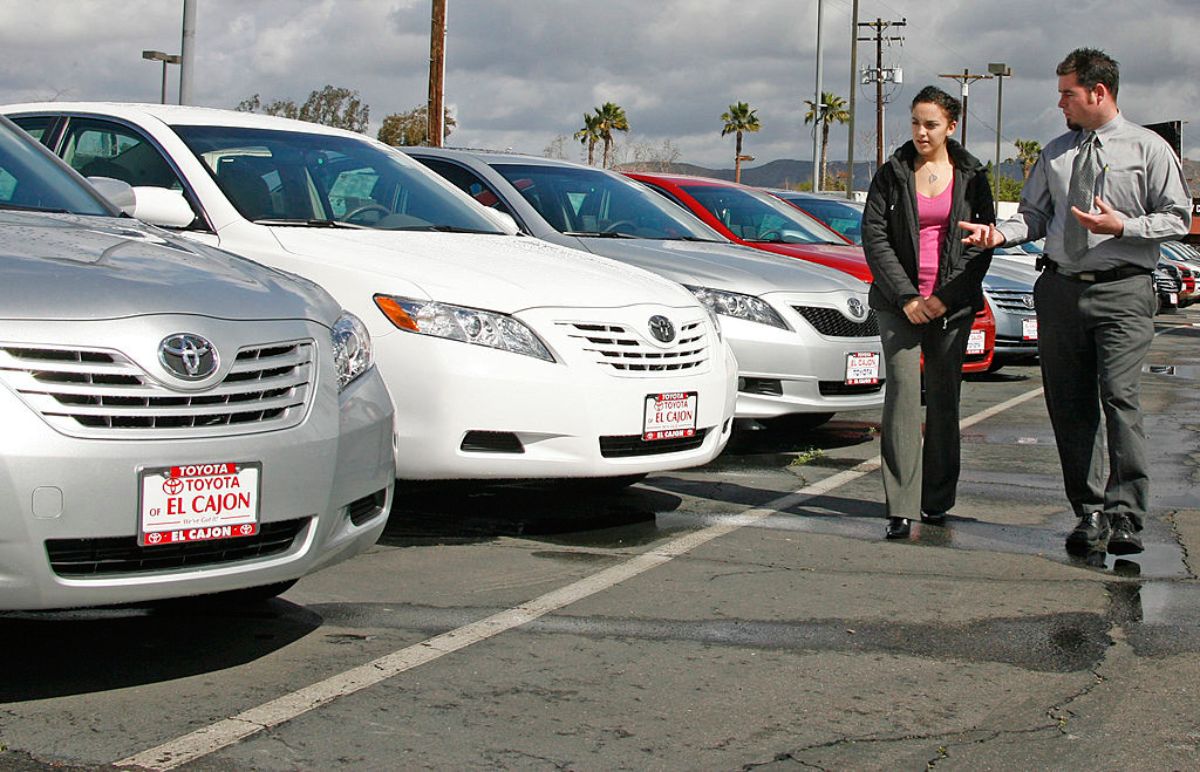 A car dealer showing used cars to a customer.