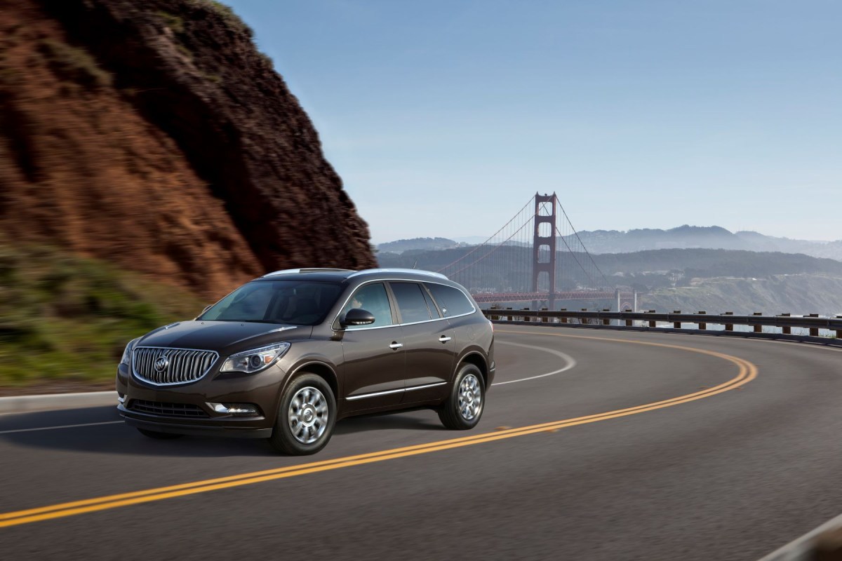 A dark brown 2013 Buick Enclave three-row luxury SUV model driving on a highway near the Golden Gate Bridge