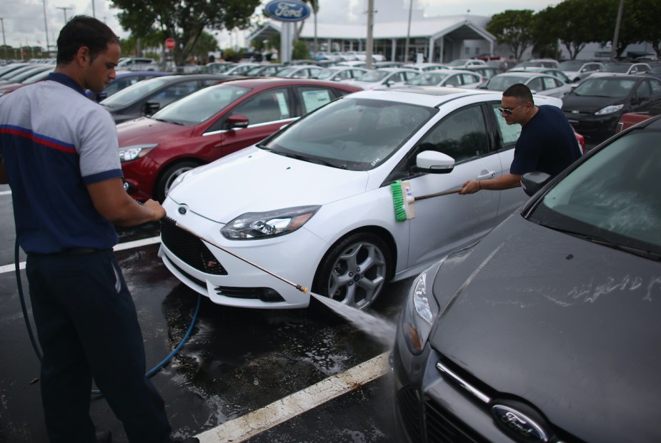 Dealership employees wash a car. 