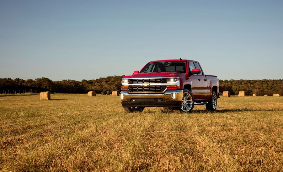 A red 2016 Chevrolet Chevy Silverado 1500 LT full-size pickup truck model parked on a farm hay field