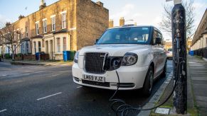 A plug-in electric Taxi EV plugged into a charging station on a residential street in London, England