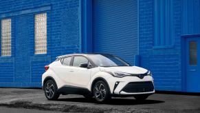 A white 2022 Toyota C-HR subcompact SUV model framed by a blue-painted brick wall