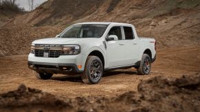 A white 2023 Ford Maverick Tremor compact pickup truck model parked near mounds of plowed dirt at a worksite