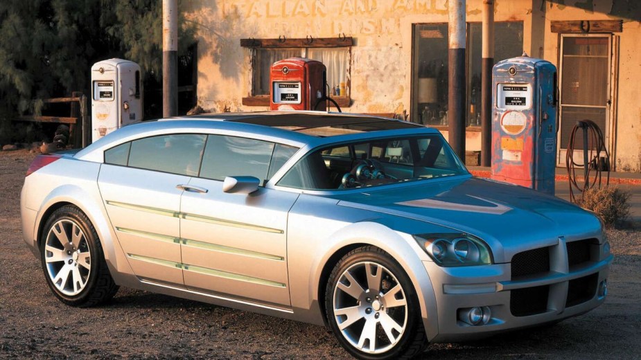 A very vintage silver 2001 Dodge concept car called the Super 8 Hemi is parked in front of a vintage gas station for a photoshoot.