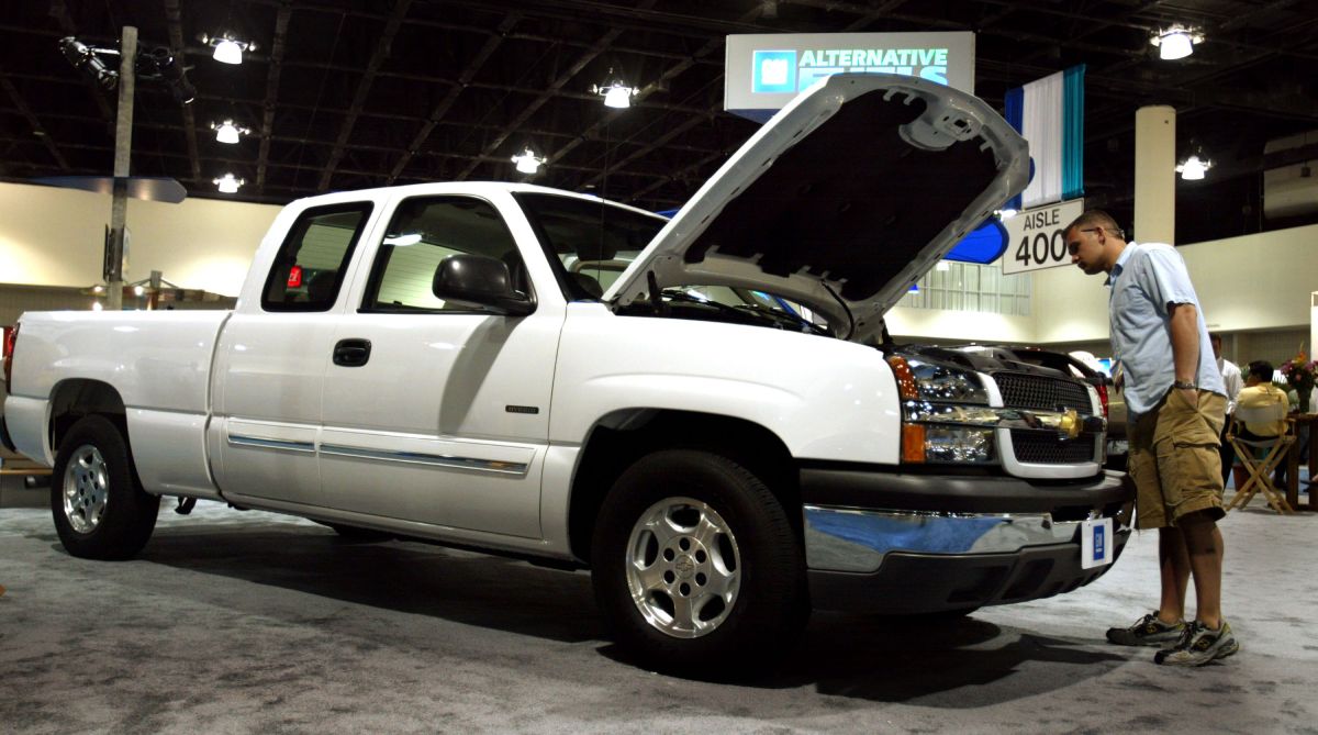 A man inspecting a 2004 Chevy Silverado at an auto show.