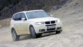 A white 2009 BMW X3 compact luxury SUV model covered in dust and dirt from driving on rocks and gravel