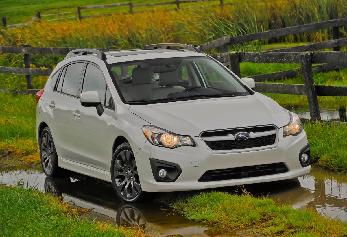 A white subaru hatchback sits in farm tracks