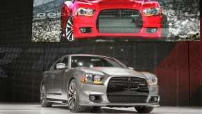 A gray 2013 Dodge Charger SRT8 poses on a stage at an auto show.