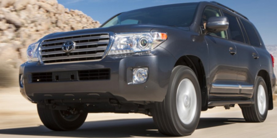 A blue 2013 Toyota Land Cruiser ifull-size SUV is driving on the road.