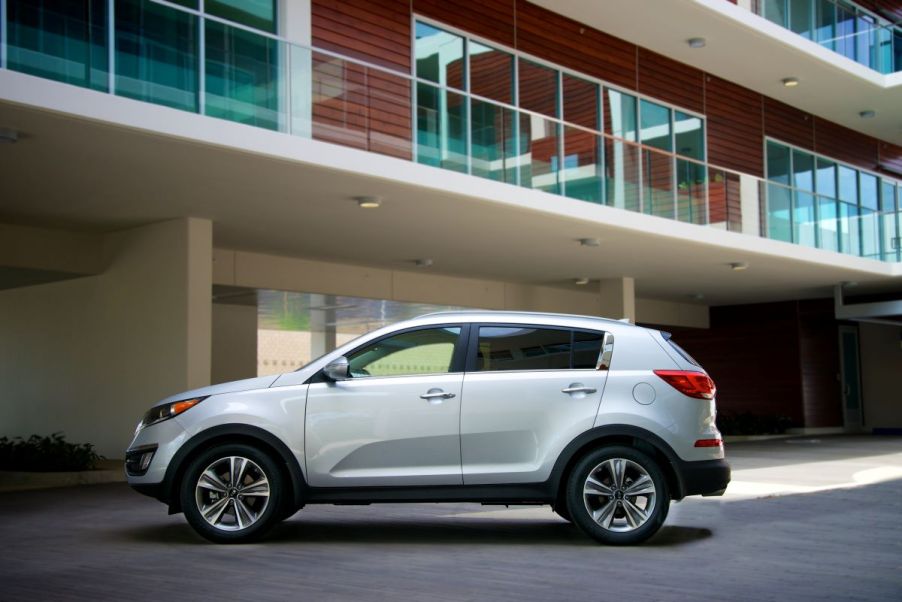 A 2015 Kia Sportage sits in a parking lot below an apartment building outlook