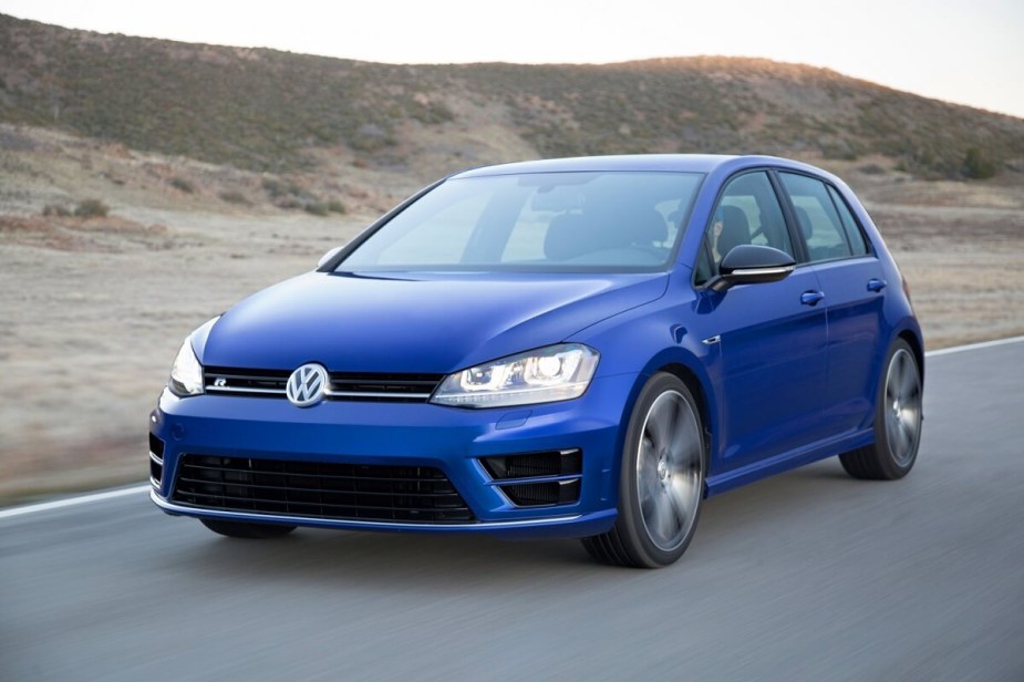 A 2015 Volkswagen Golf R, a cheap fast used car, blasts down a back road while it shows off its blue paintwork. 