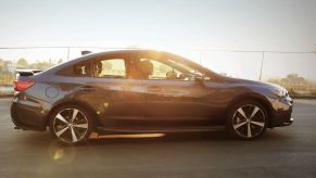 A gray 2018 subaru sedan drving down a sunny road.