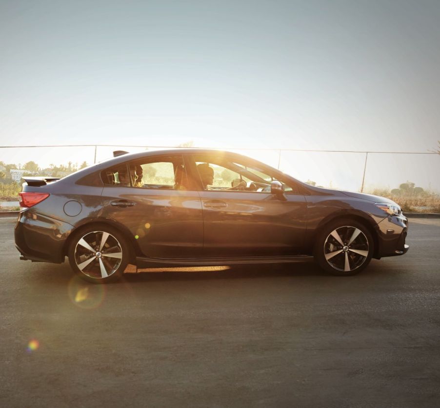 A gray 2018 subaru sedan drving down a sunny road.