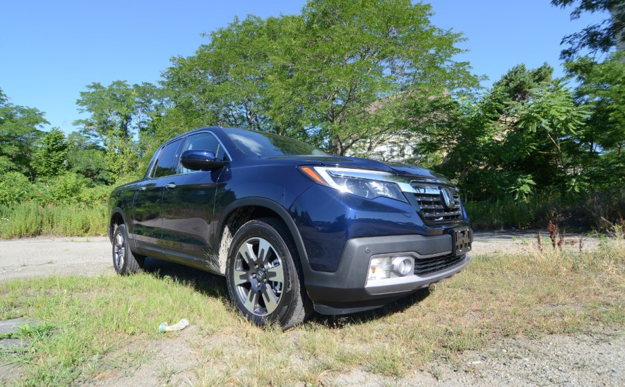 A 2019 Honda Ridgeline sits in a field. You can find this used truck for less than $30,000.