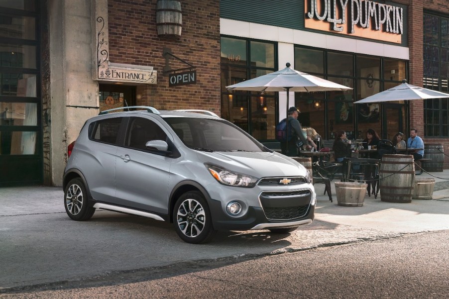 A silver 201 Chevrolet Spark parked out doors, which is the Chevrolet with the lowest insurance cost.