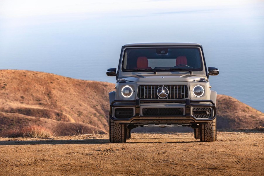 This is a promo photo of a 2021 G Class SUV parked on a sand dune in front of the ocean.