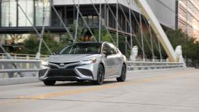 A brand new Toyota Camry, one of the car company's most popular cars, shows off its silver paintwork as it cruises city streets.