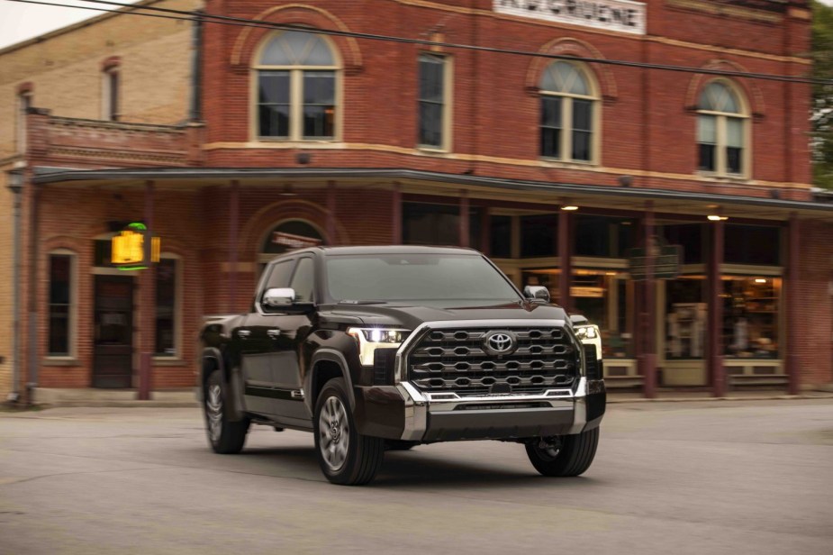 Brown 2022 Toyota Tundra 1794 Edition driving in front of a brick building front.