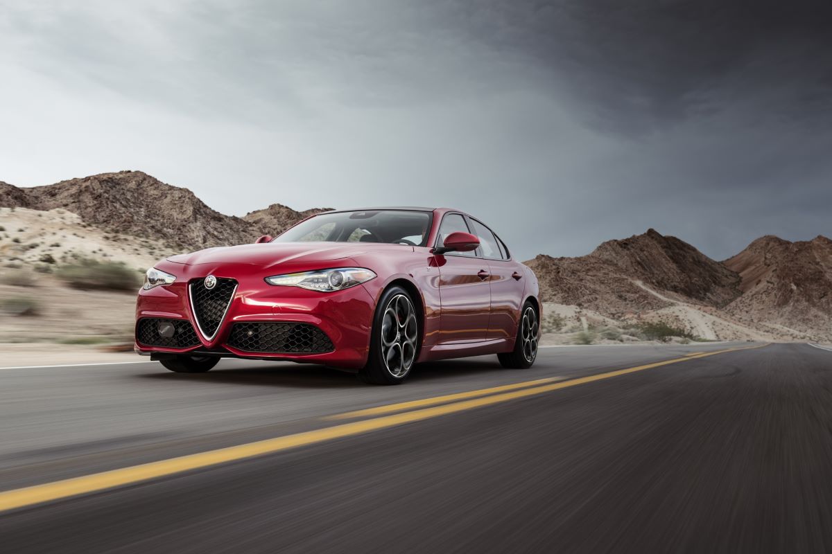 A red 2023 Alfa Romeo Giulia driving on a open road.