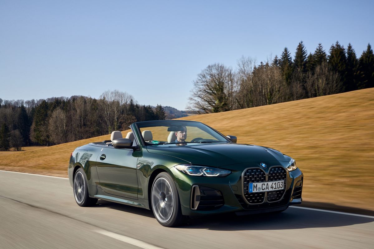 A green 2023 BMW M440 xDrive Convertible drives down a road