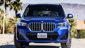 A blue 2023 BMW X1 driving down the road.