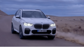 2023 BMW X5 in white driving down the road at dusk