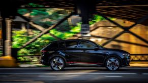 A side exterior profile shot of a 2023 Dodge Hornet plug-in hybrid (PHEV) compact SUV model driving under a bridge