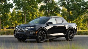 A black 2023 Hyundai Santa Cruz truck parked in a green area.